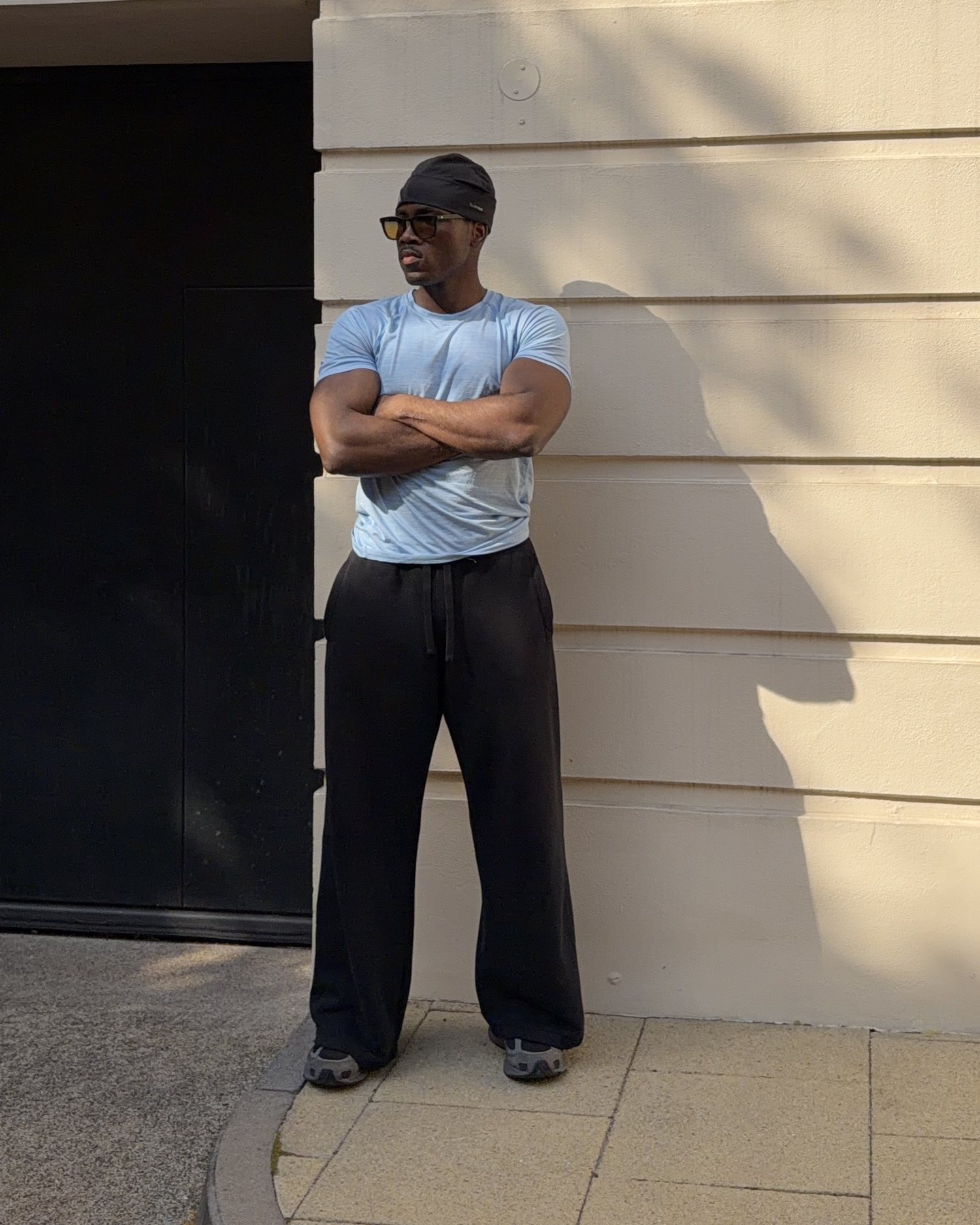 Ozzy Bern standing with arms crossed against a cream wall